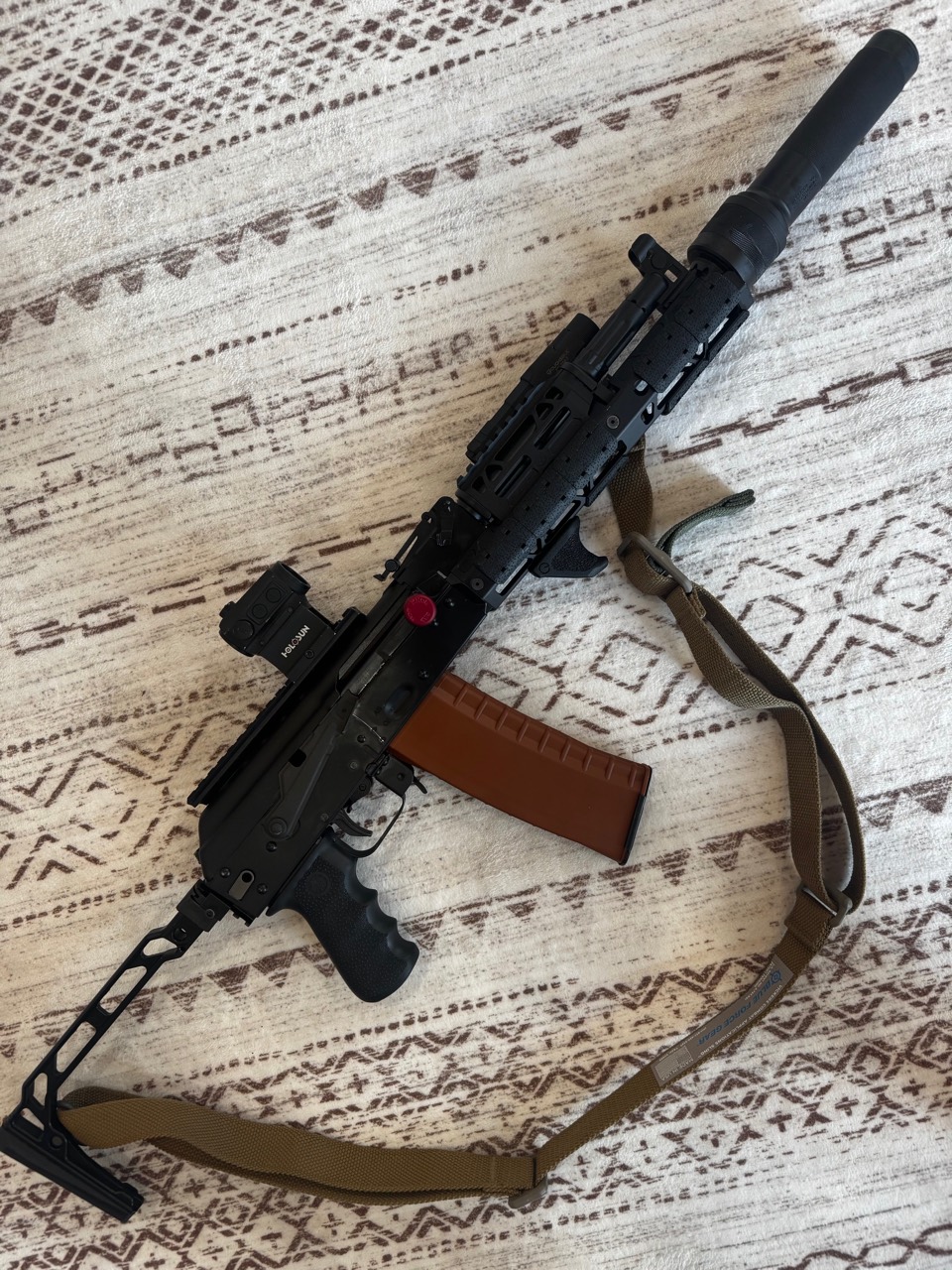 Cody's current AK-102 configuration with skeleton stock, optic, brown magazine, railed handguard, sling, and suppressor