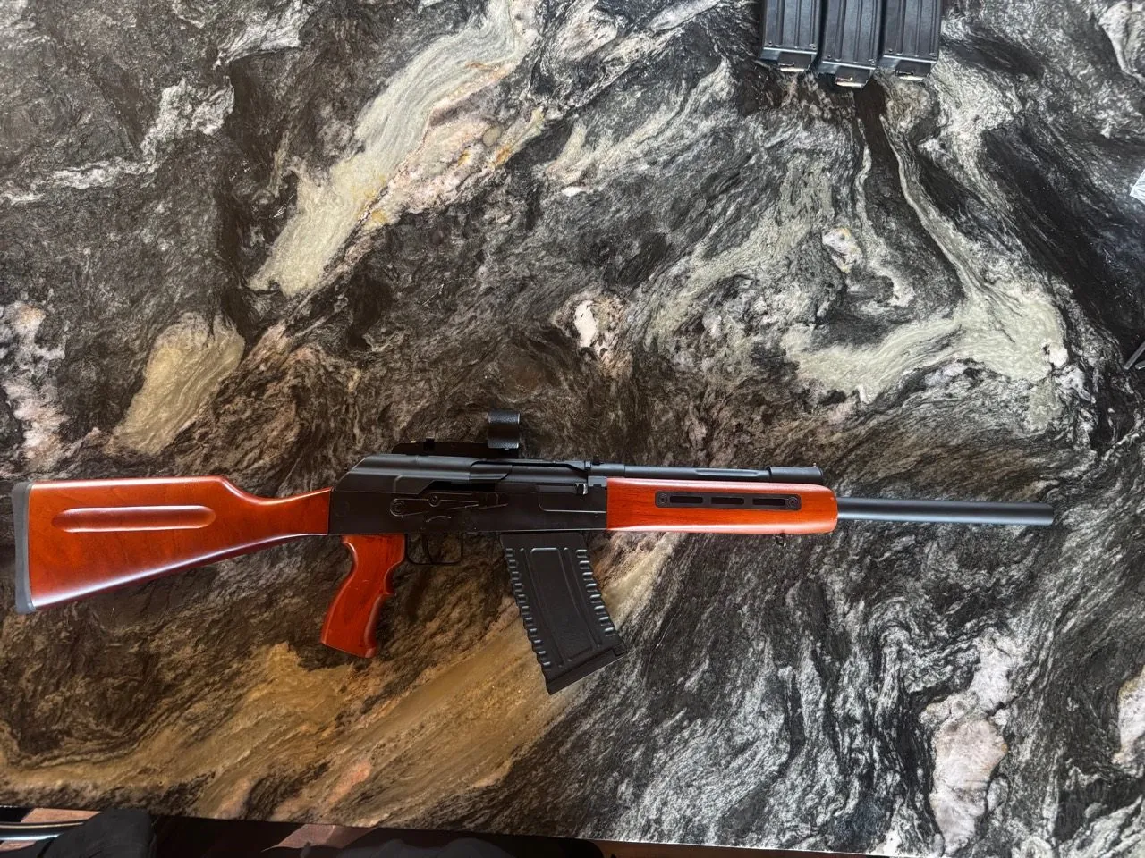 Saiga-12 pattern shotgun with wood furniture on a stone-pattern bench