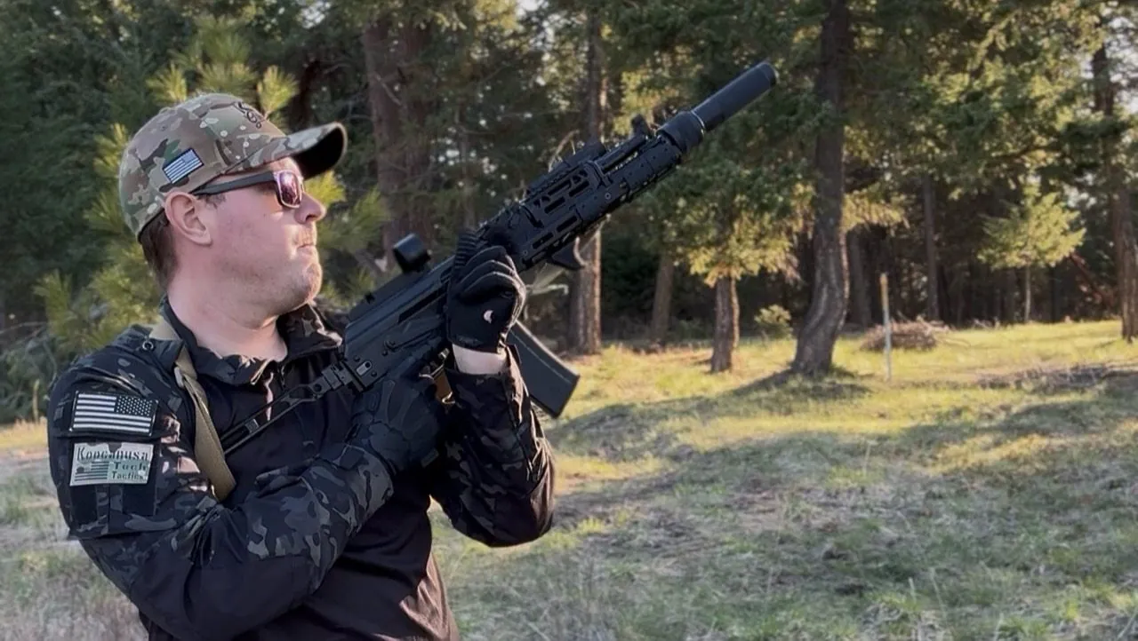 Cody holding a rifle outdoors in timber