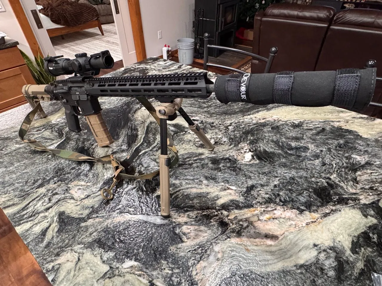 Custom AR on a bench with optic and covered muzzle device