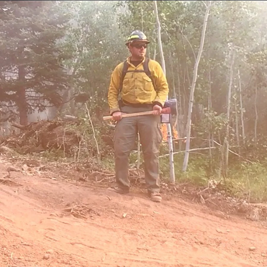 Cody Rhoads in yellow Forest Service field shirt holding a hand tool